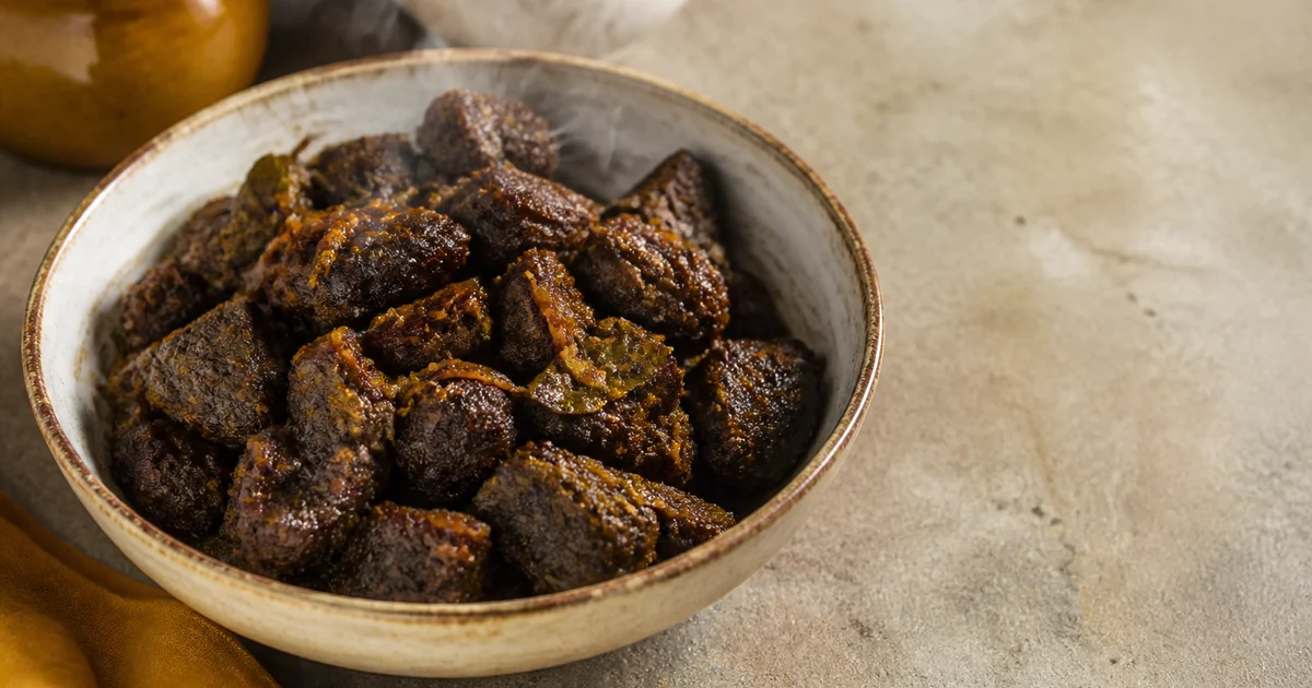 Deep dark-brown Chattogram-style beef kala bhuna with tender beef pieces, roasted masala, green chillies and separated oil.