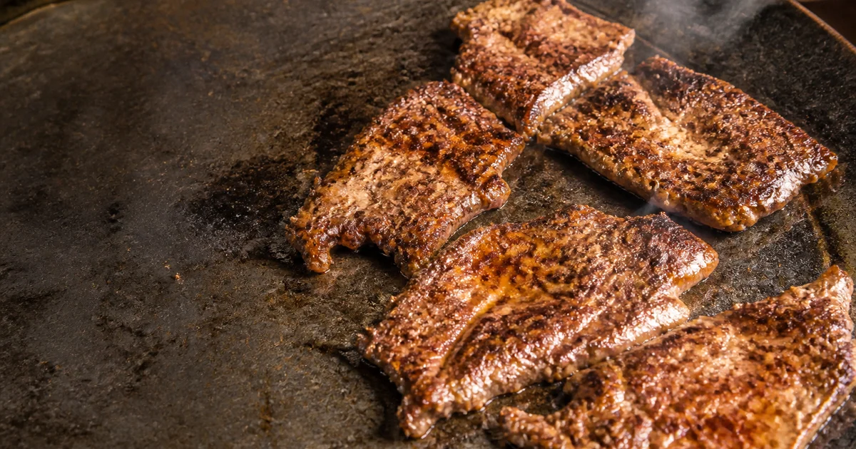 Flattened Bangladeshi beef chaap coated in dark tawa masala and served hot with layered paratha, onion and lemon.