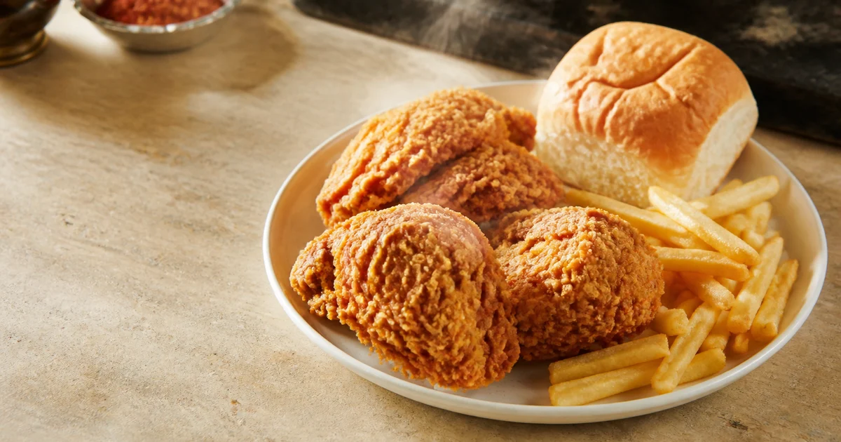 Golden chicken broast quarter served with crisp fries, a soft bun and mayonnaise on a restaurant plate.