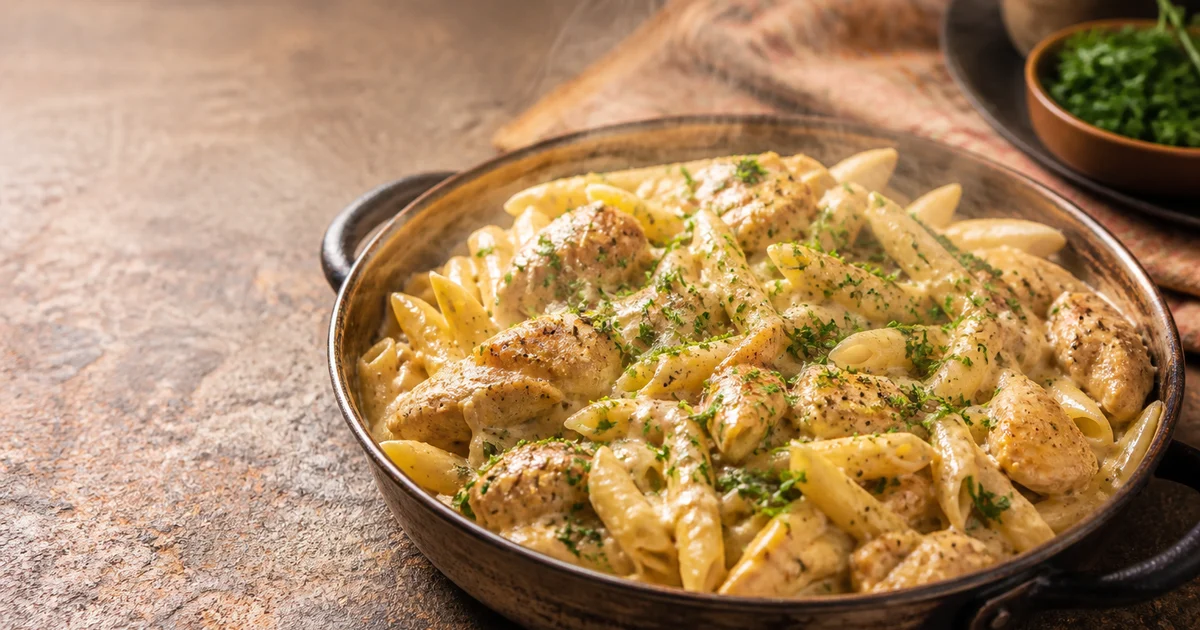 A restaurant portion of creamy penne pasta with chicken strips, capsicum and a smooth cheese sauce.