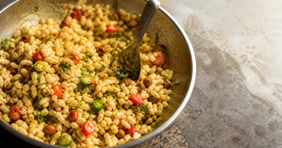 A fresh plate of Bangladeshi jhalmuri with puffed rice, chanachur, peanuts, potato, onion, cucumber, coriander and green chilli.