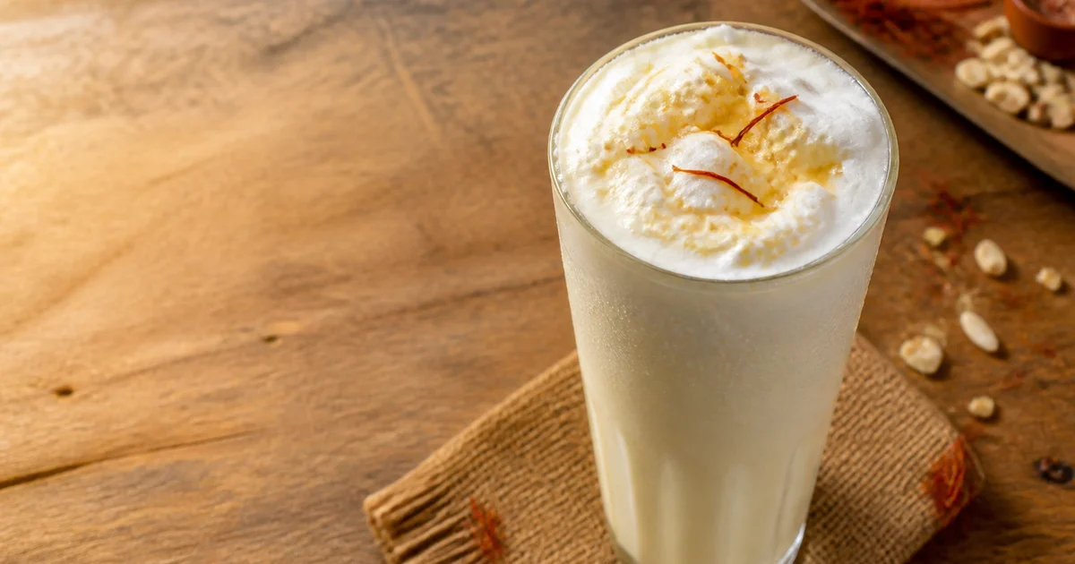 Chilled sweet lassi served in clear cups with a smooth creamy surface and a light cardamom garnish.