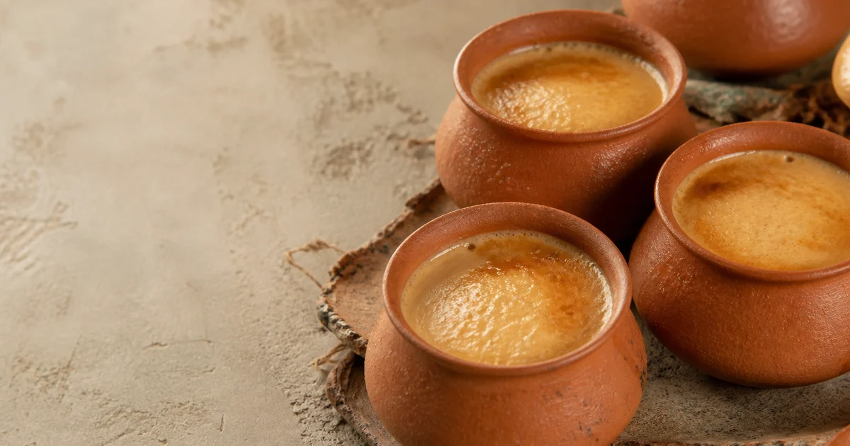 Deep caramel-coloured Bangladeshi mishti doi set in individual unglazed earthen pots.