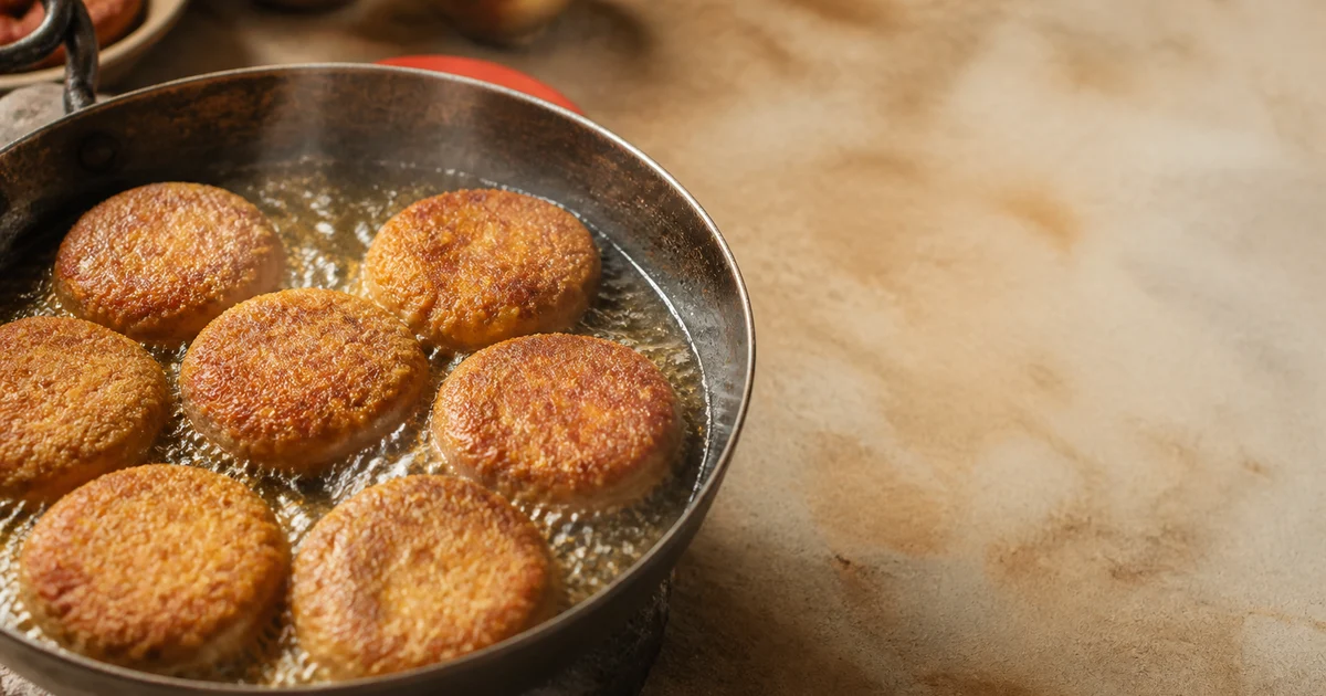 Golden-brown Bangladeshi beef shami kebabs arranged on a serving plate with fresh coriander and green chillies.