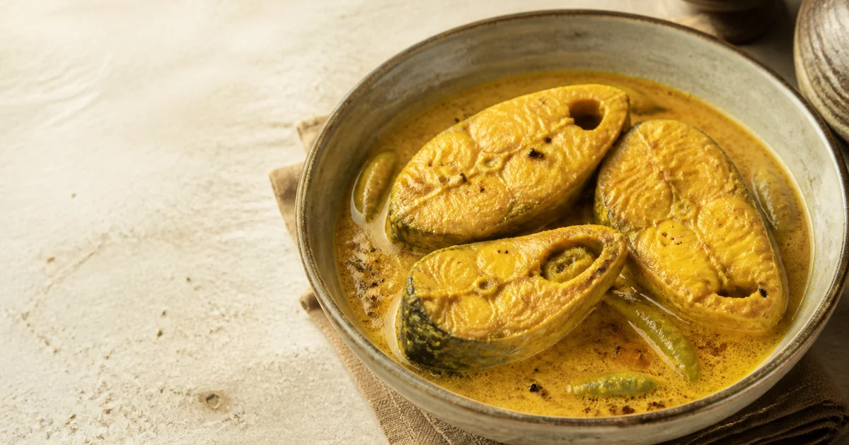 Bone-in hilsa steaks cooked in golden mustard sauce with green chillies and mustard oil.