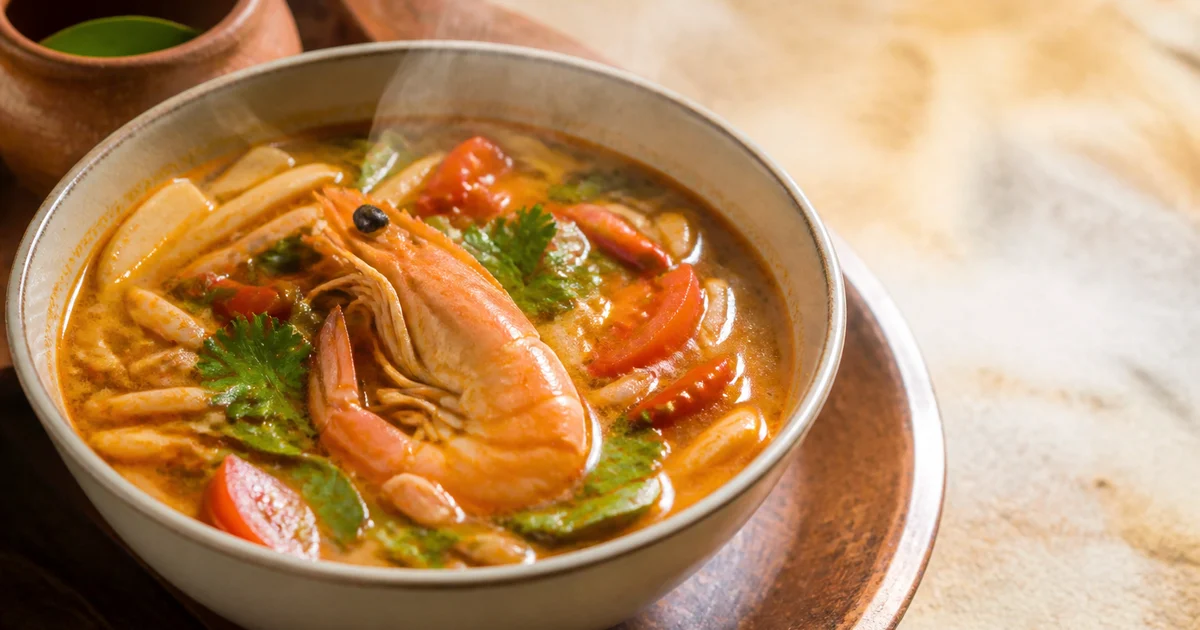 A bowl of thick hot-and-sour Thai soup with chicken, prawns, mushrooms, carrots, capsicum and coriander.